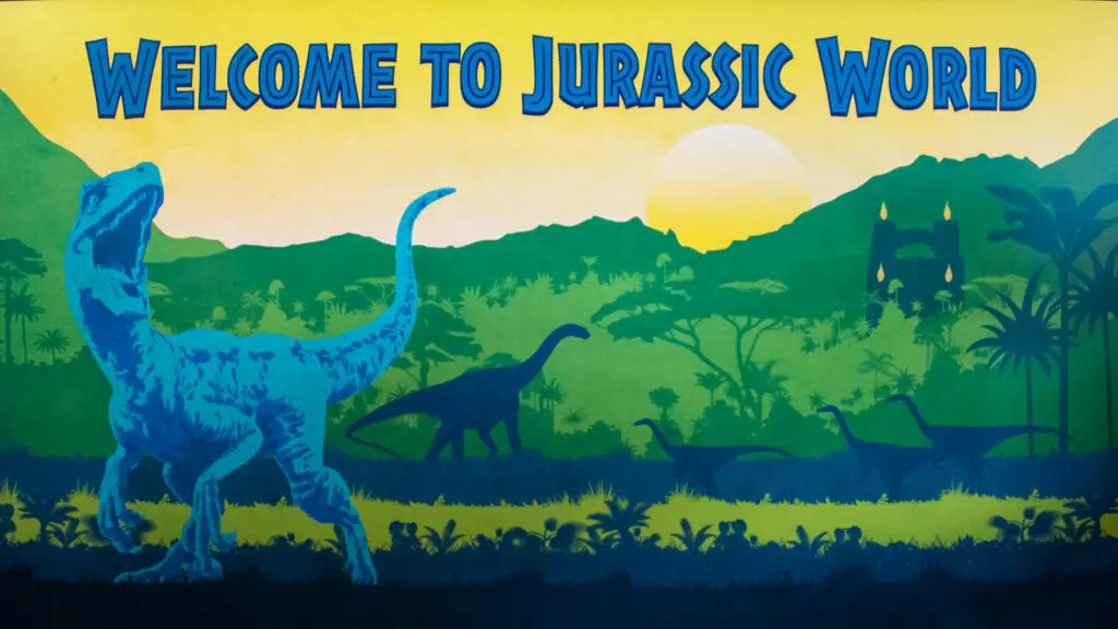 Illustration depicting dinosaurs in a prehistoric landscape with the text "Welcome to Jurassic World" against a backdrop of mountains, trees, and a setting sun.
