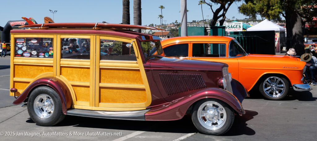 A classic wood-paneled station wagon and an orange vintage Chevrolet car are parked side by side at an outdoor car show.