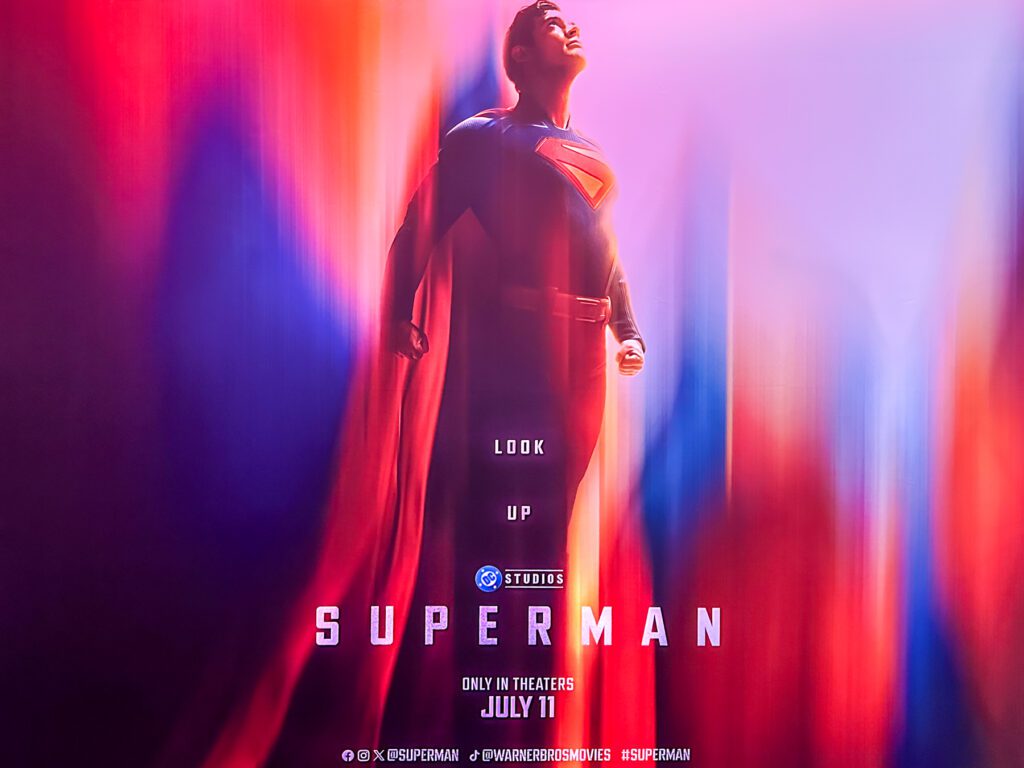 A promotional poster showing Superman standing with his cape flowing, looking upward, with the text "Look Up," "Superman," and "Only in theaters July 11.