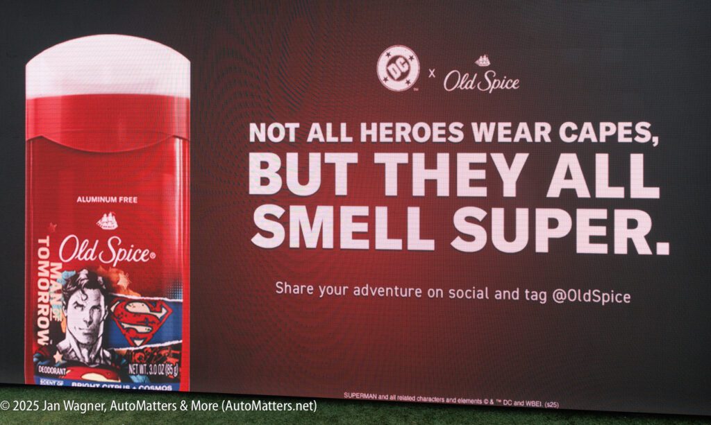 A billboard advertises Old Spice deodorant with a Superman-themed design and the slogan, "Not all heroes wear capes, but they all smell super.
