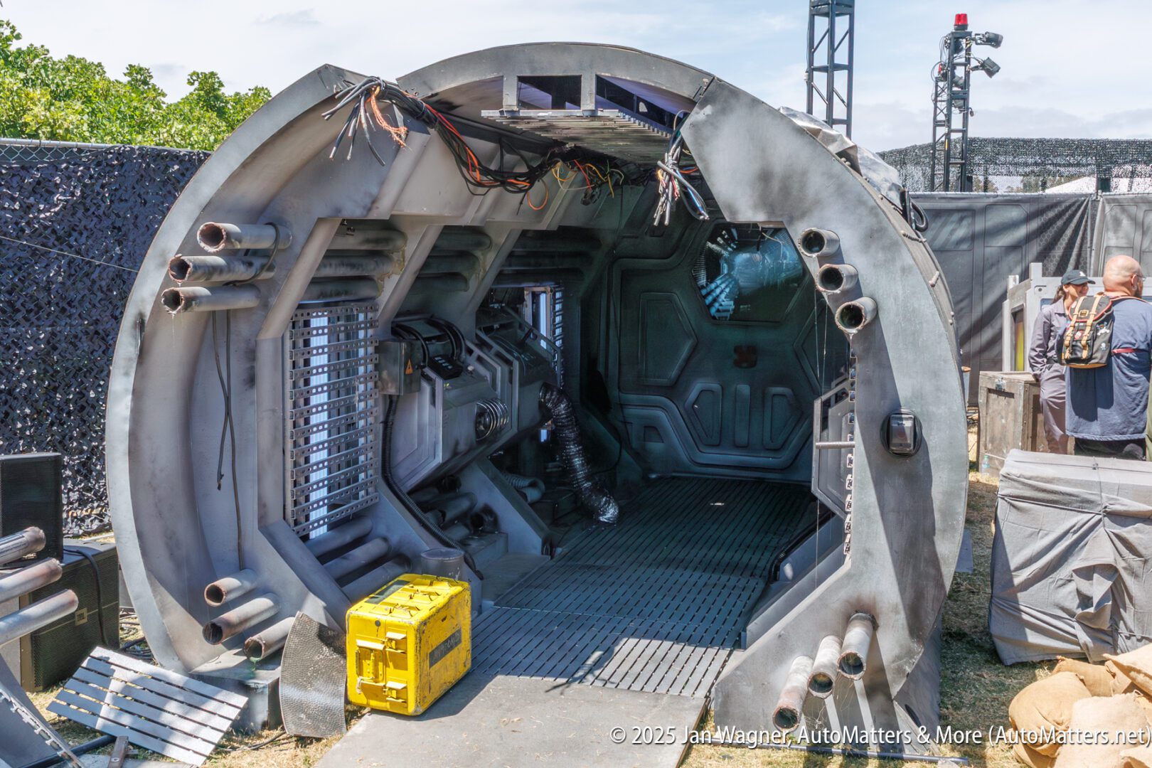 A sci-fi themed set resembling a metallic spaceship or bunker interior, with exposed pipes and a yellow storage box on the ground outside the entrance.