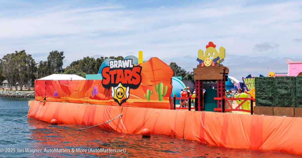 A colorful floating platform on water features "Brawl Stars" branding and themed decorations, with people and other structures visible in the background.