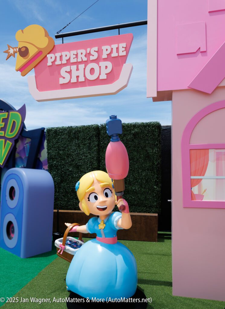 A cartoonish statue of a girl in a blue dress holding a large pie-themed object stands outside a building with a sign reading "Piper's Pie Shop.