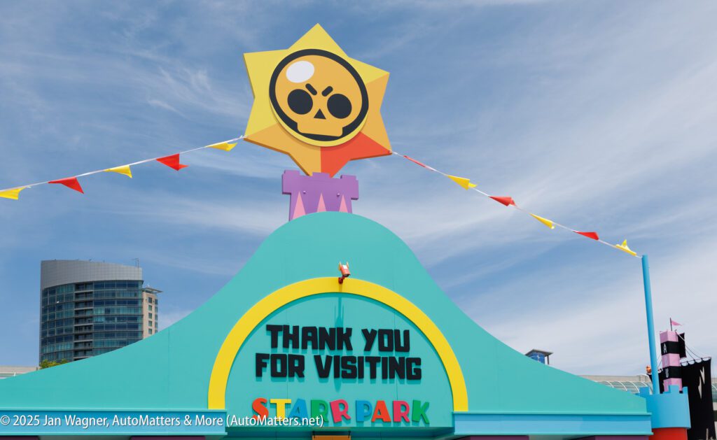 Colorful sign at an amusement park entrance reading "THANK YOU FOR VISITING STARR PARK" with decorative elements and a building in the background.