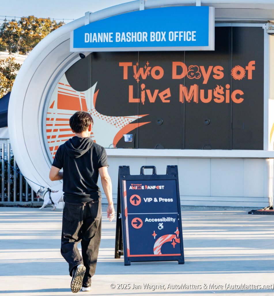 A person walks toward a box office with a sign reading "Two Days of Live Music." An informational sandwich board is placed in front.