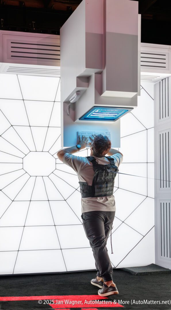 A person in a vest uses a futuristic wall-mounted keyboard and screen, standing in front of a geometric lighted backdrop.