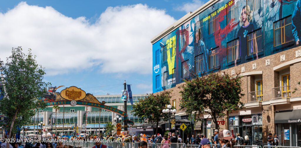 Street view of San Diego's Gaslamp Quarter during Comic-Con, with a large mural on a building, crowds, and event signage visible.