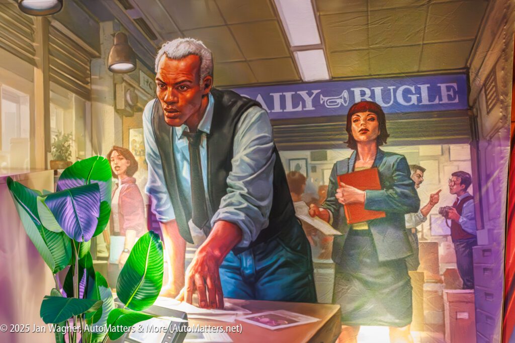 Two people stand in a busy office labeled "Daily Bugle"; one leans over a desk with papers, another holds a folder, with others working in the background and a plant in the foreground.