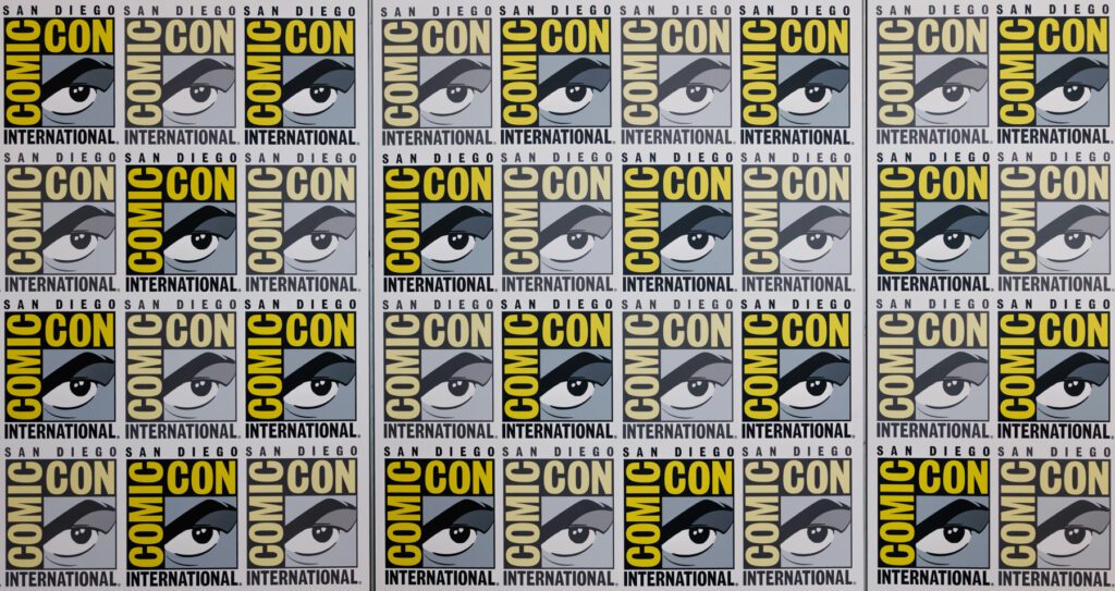 Comic-Con International: San Diego logo repeated in a grid pattern, featuring a stylized eye and bold yellow and black text.