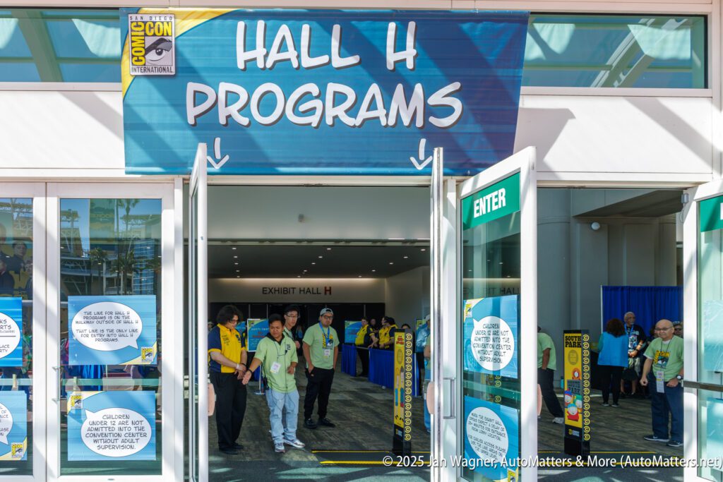 Entrance to Hall H Programs at San Diego Comic-Con, with staff and attendees standing near open doors under a large event sign.
