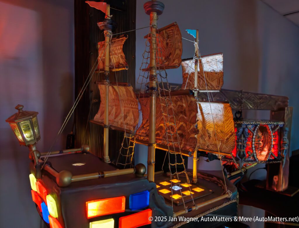 A detailed model of a wooden sailing ship with illuminated sections and intricate rigging, displayed indoors.