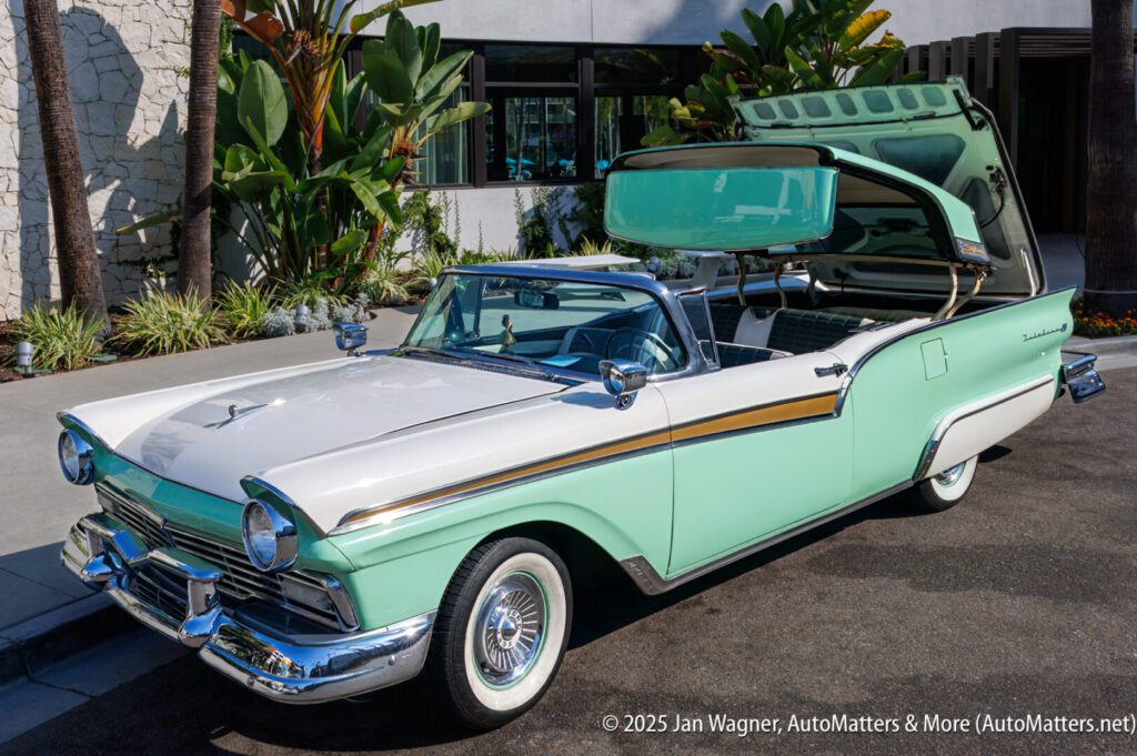 A vintage two-tone green and white Ford Fairlane Skyliner convertible with its retractable hardtop roof partially open, parked on a sunny street near tropical plants.