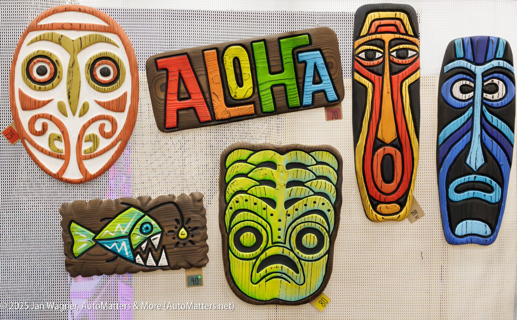 Colorful tiki mask art and an "ALOHA" sign are displayed on a white textured background.