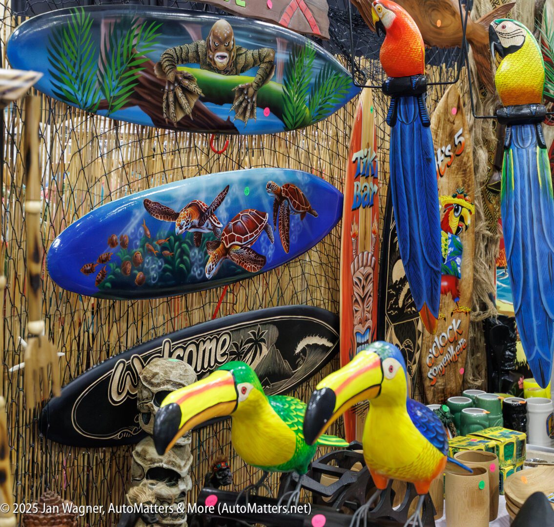Colorful display featuring surfboards with sea turtle designs, toucan and parrot decorations, tiki masks, and other tropical-themed items at a market stall.