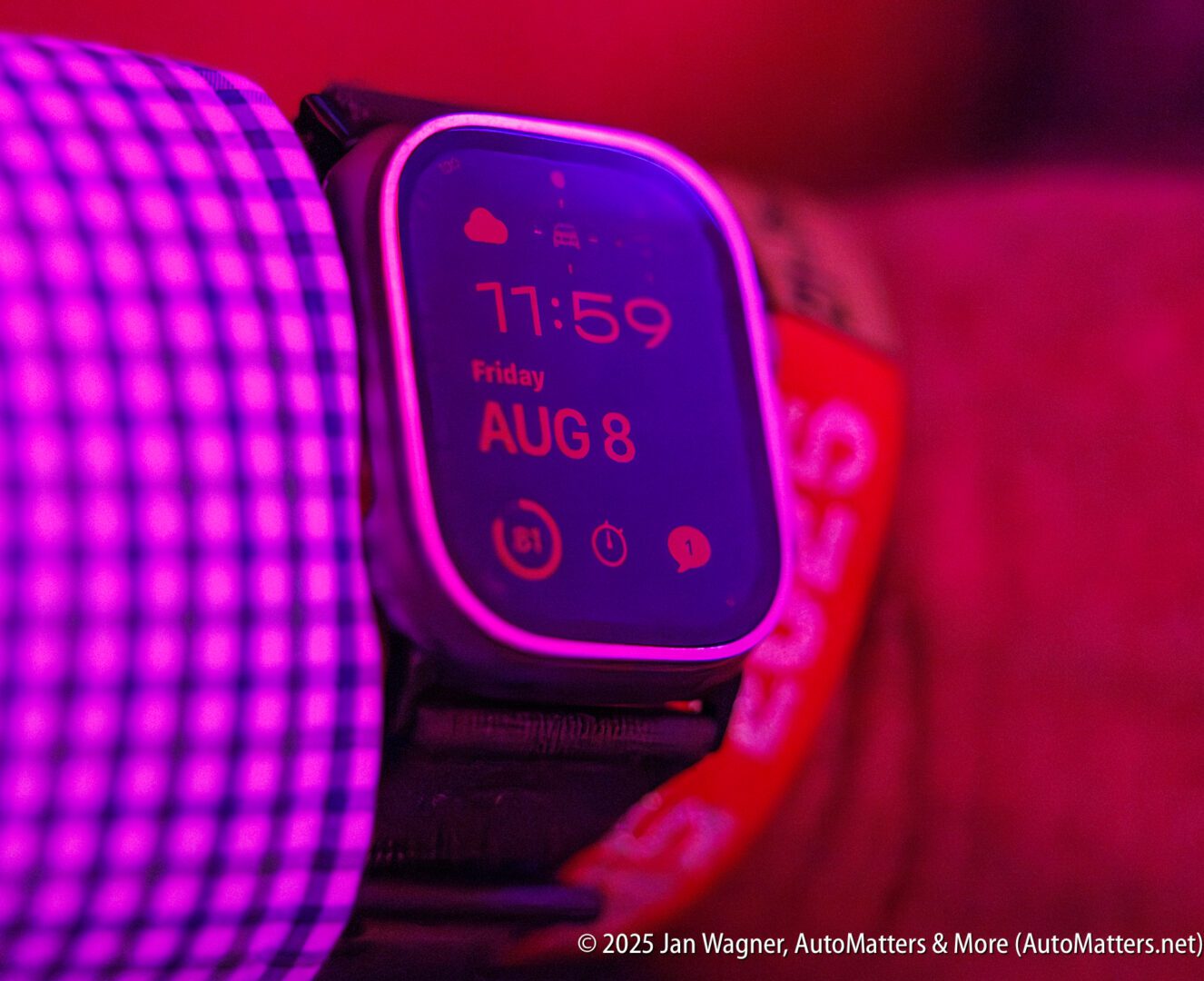 A close-up of a smartwatch displaying the time 11:59 on Friday, August 8, worn on a wrist under purple lighting.