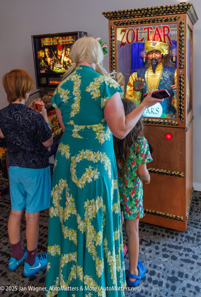 A woman and two children stand in front of a Zoltar fortune teller machine in an arcade.