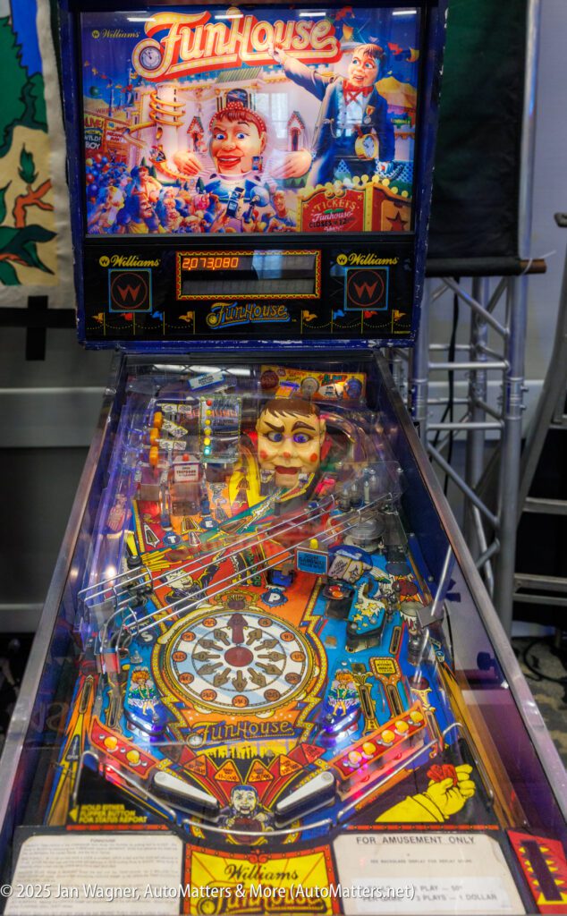 A FunHouse pinball machine with colorful artwork, a large animated face, and various bumpers and flippers under a glass cover.