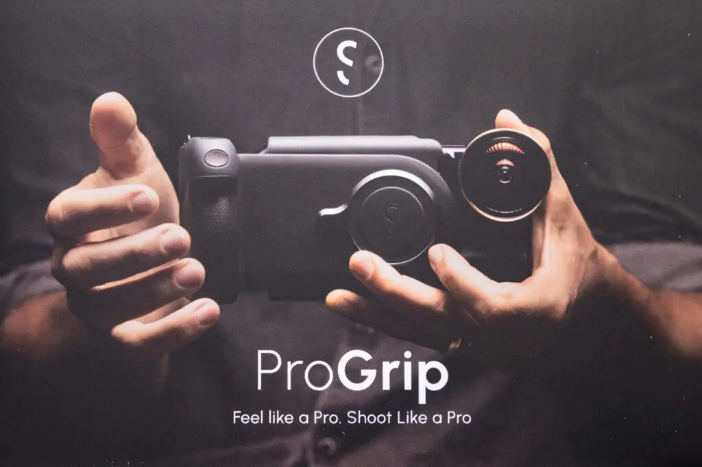 A person holds a ProGrip camera accessory with a lens attached; text below reads "ProGrip. Feel like a Pro. Shoot Like a Pro.