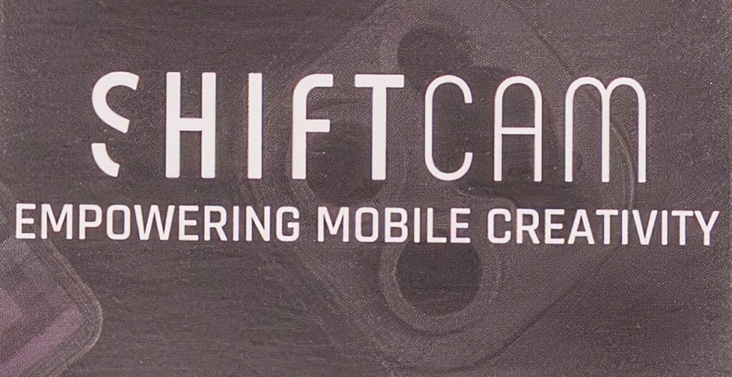 The image displays the text "SHIFT CAM EMPOWERING MOBILE CREATIVITY" on a textured background with faint outlines of camera lenses.