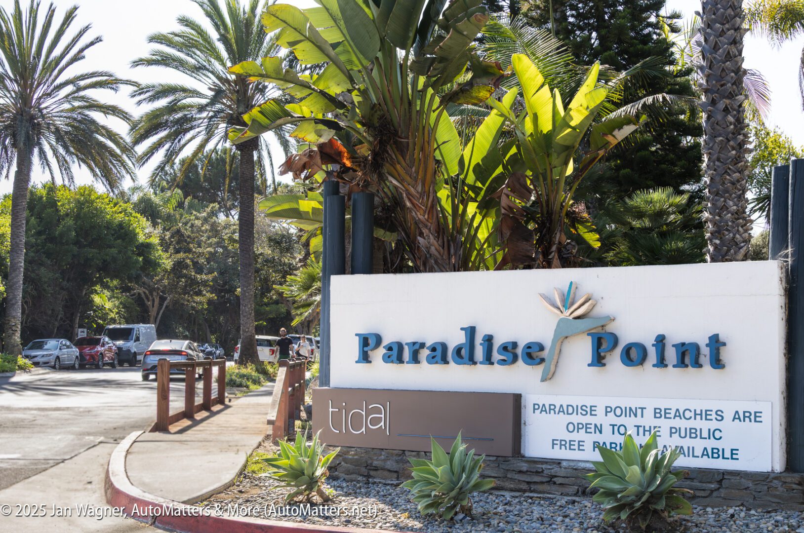 Entrance sign for Paradise Point with palm trees in the background; the sign notes public beach access and available free parking.