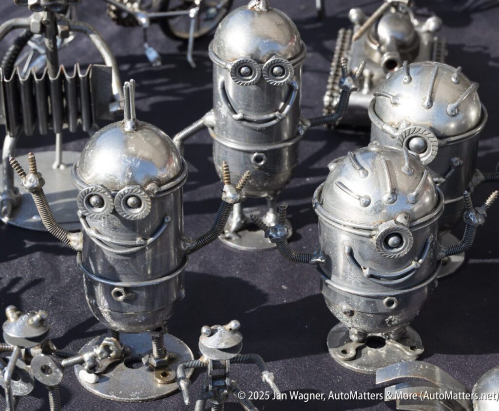 Several small robot figurines made from metal parts are displayed on a surface, featuring bolts, springs, and gears as their components.