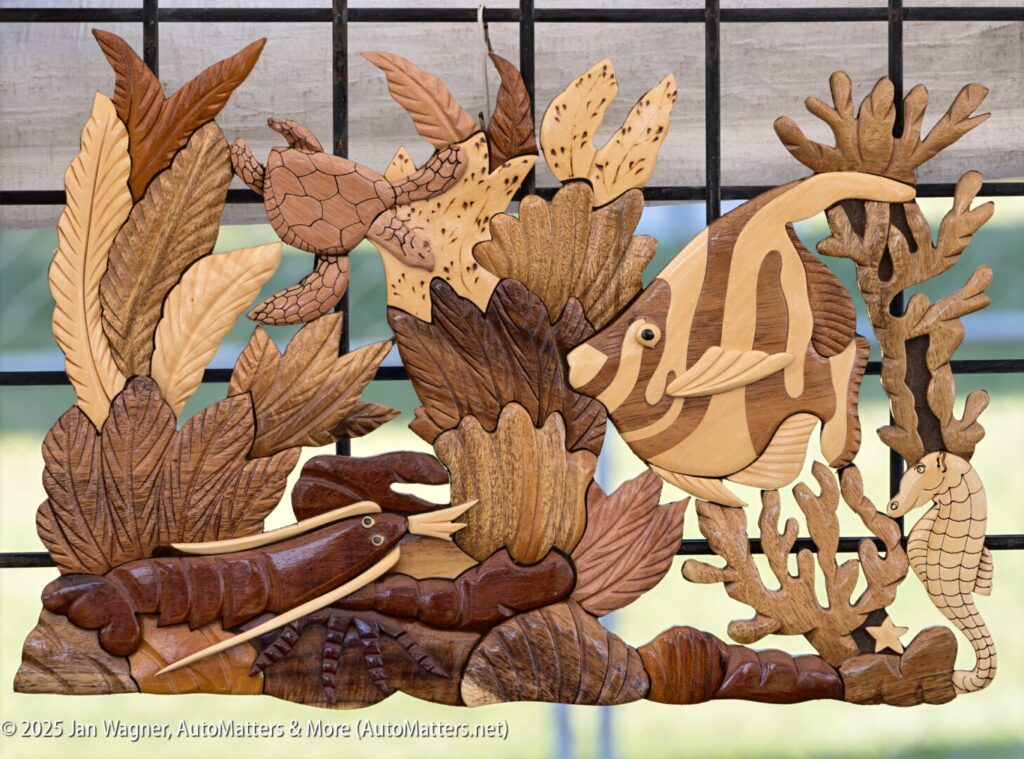 Wooden wall art depicting an underwater scene with a turtle, angelfish, lobster, seahorse, coral, and sea plants, set against a metal grid background.