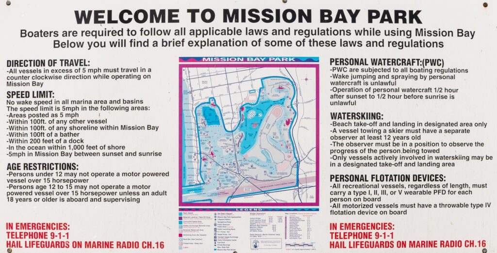 Informational sign at Mission Bay Park provides boating rules, speed limits, age restrictions, regulations, emergency contacts, and detailed map of the bay with designated areas.