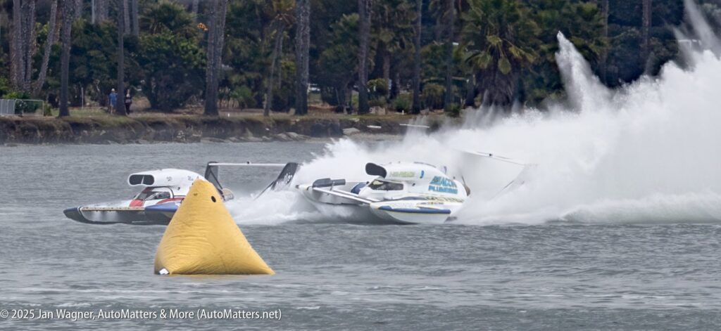 Two hydroplane boats collide at high speed on a racecourse, causing a spray of water; a yellow buoy is visible in the foreground.