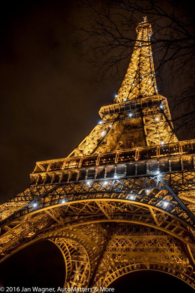 The Eiffel Tower illuminated at night, photographed from a low angle with lights highlighting its structure against a dark sky.