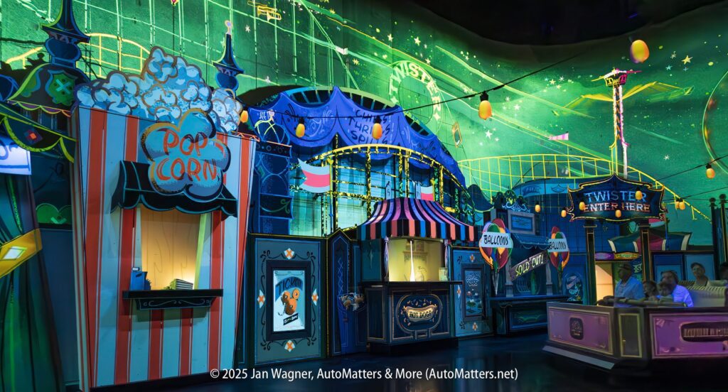 Colorful carnival-themed amusement ride scene with popcorn and balloon booths, striped tents, and patrons seated in a Twister ride car. Bright green and blue lighting effects illuminate the area.