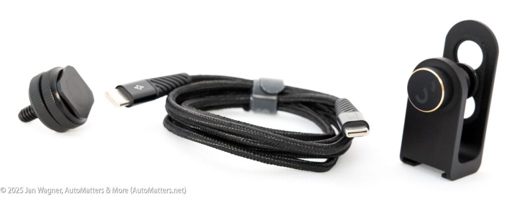 A black USB-C charging cable, a magnetic phone mount, and a black phone holder are displayed on a white surface.