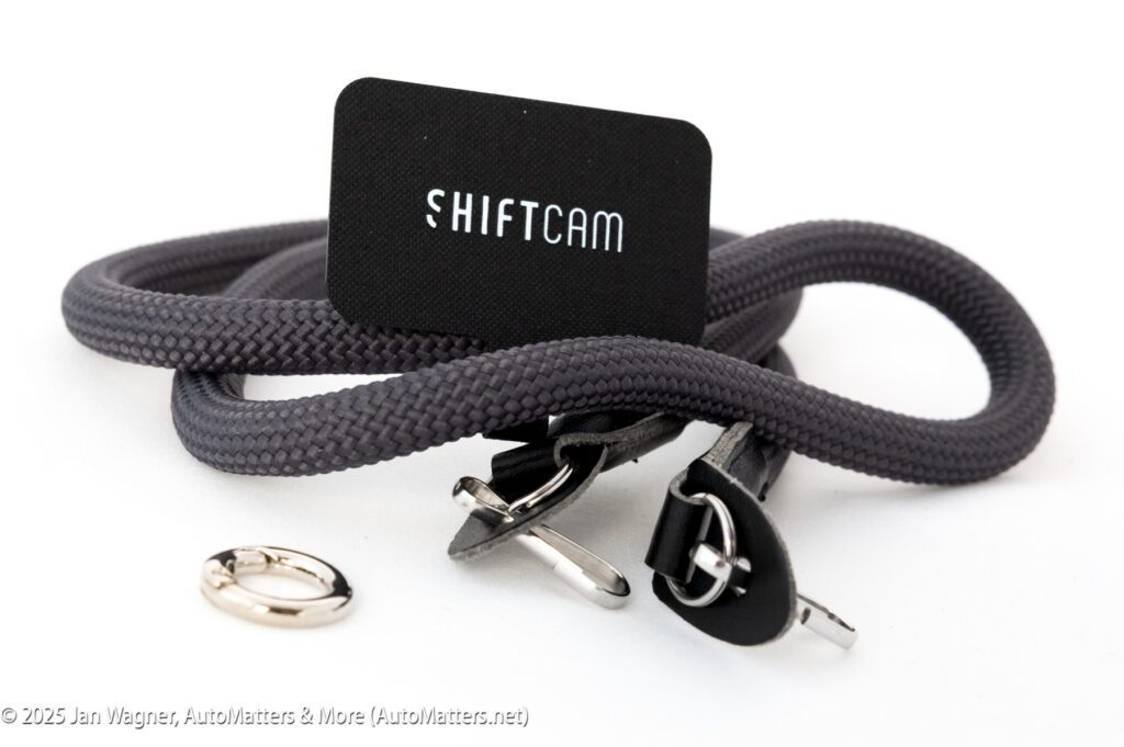 A coiled gray ShiftCam strap with metal clips, a metal ring, and a black ShiftCam-branded card on a white background.