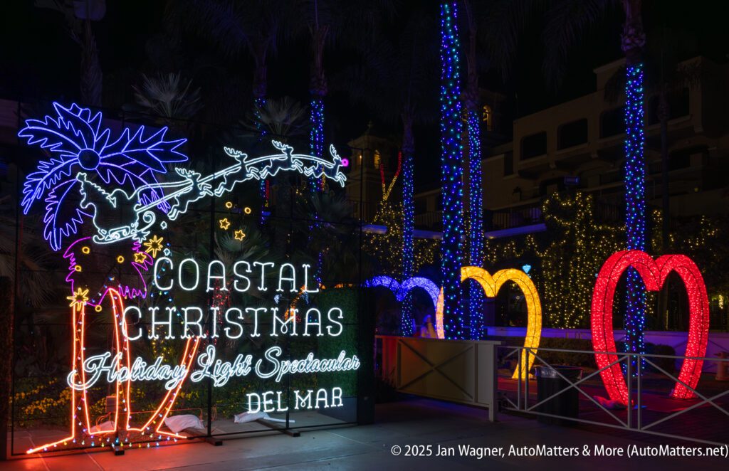Neon holiday light display reading "Coastal Christmas Holiday Lights Spectacular Del Mar" with palm tree, Santa, and reindeer decorations surrounded by colorful lights.