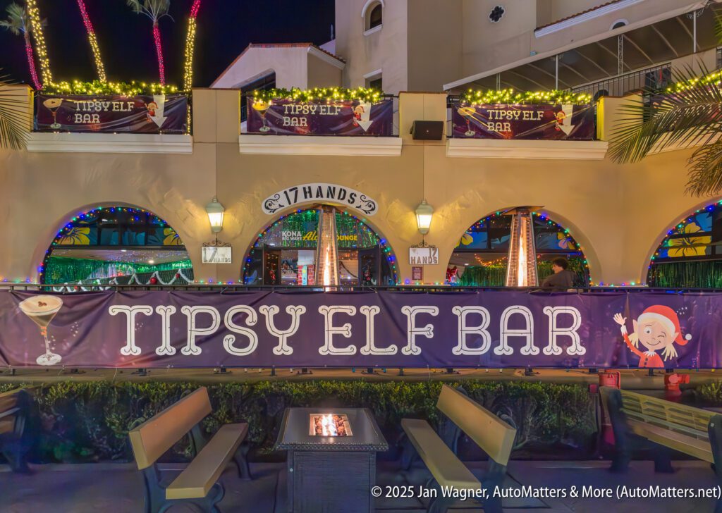 Outdoor view of Tipsy Elf Bar at night, with festive lights, holiday decorations, and seating area in front.