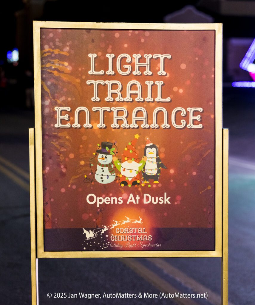 A sign reads "Light Trail Entrance Opens at Dusk" with illustrations of a snowman, reindeer, and penguin, and the Coastal Christmas logo at the bottom.