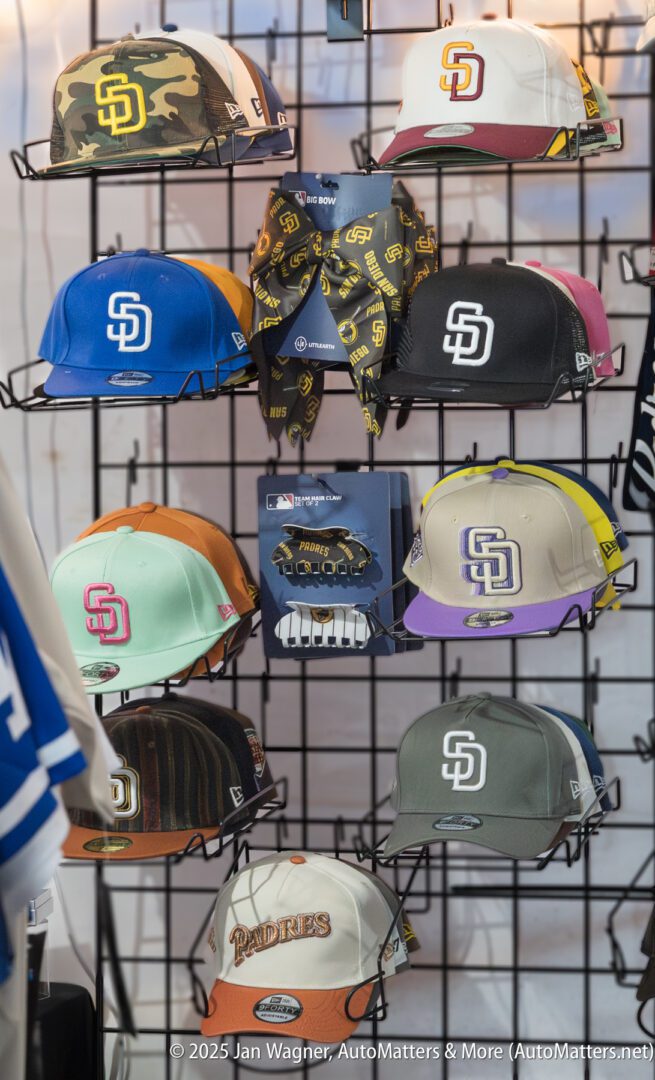 Display of various San Diego Padres baseball caps in different colors and designs arranged on a metal grid rack.