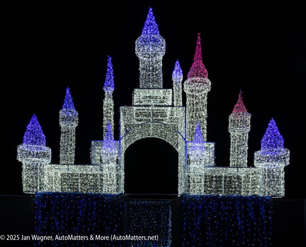 A castle structure outlined with white, blue, and pink holiday lights is displayed against a black background.