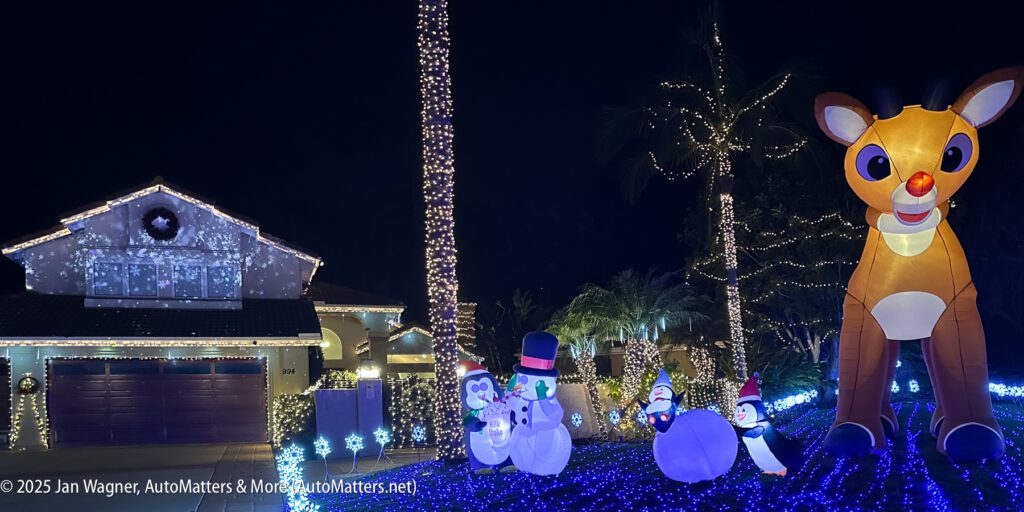 A house and yard decorated with Christmas lights, glowing snowmen inflatables, and a large inflatable reindeer at night.