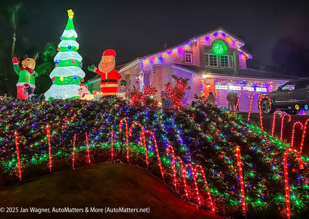 A house decorated with colorful Christmas lights, inflatable figures, and illuminated candy canes, with holiday displays on the lawn and garage.