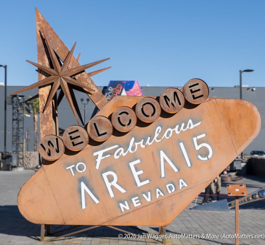 A rusted sign reads "Welcome to Fabulous AREA15 Nevada," styled like the Las Vegas sign, with buildings and a clear sky in the background.