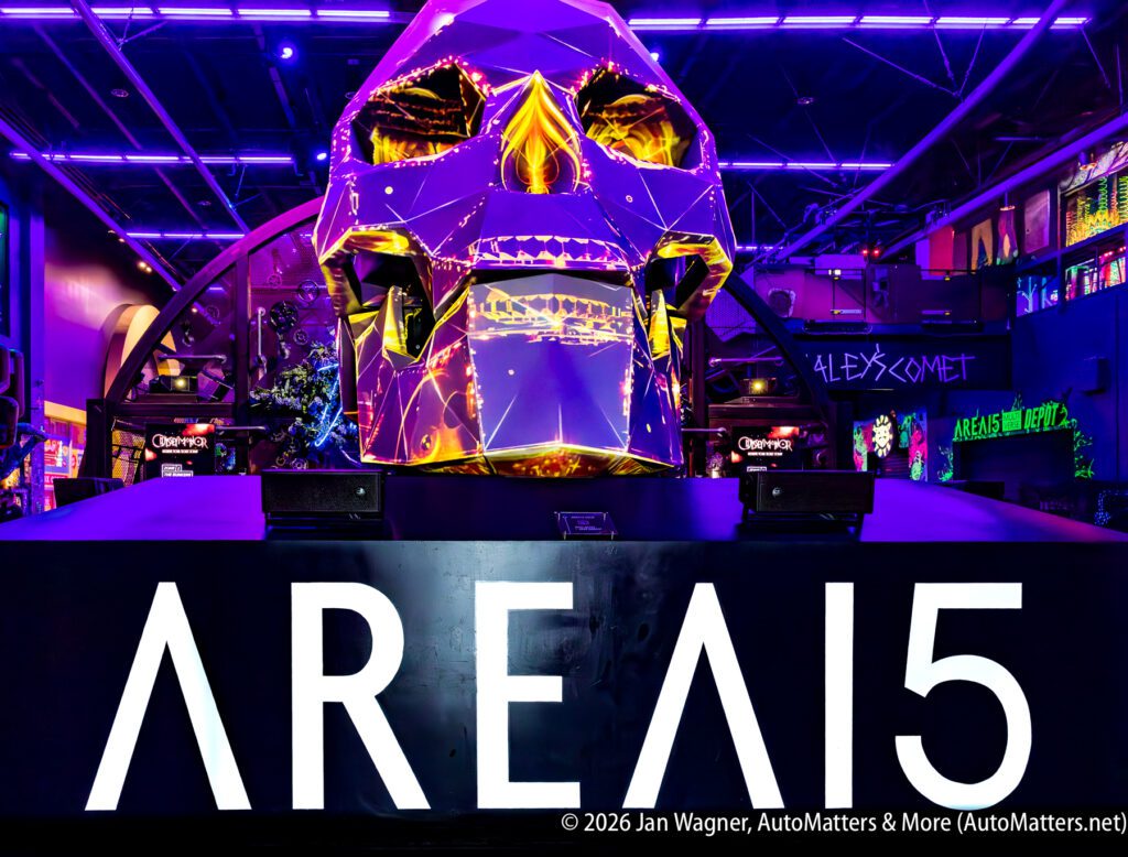 Large illuminated geometric skull sculpture with vivid purple and yellow lighting, displayed above a sign reading “AREA15” in a dark, neon-lit indoor venue.