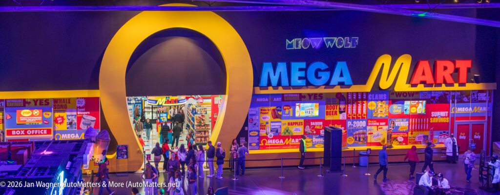 A colorful entrance to Meow Wolf's Omega Mart, featuring a large yellow portal and bright signage above a busy scene with visitors inside and outside the store.