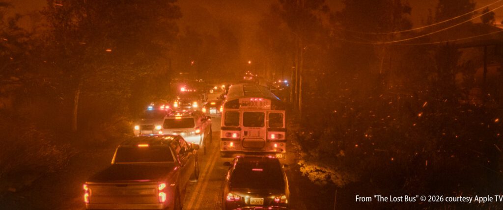 A traffic jam of vehicles, including a bus, is seen on a smoky road at night, illuminated by emergency lights.