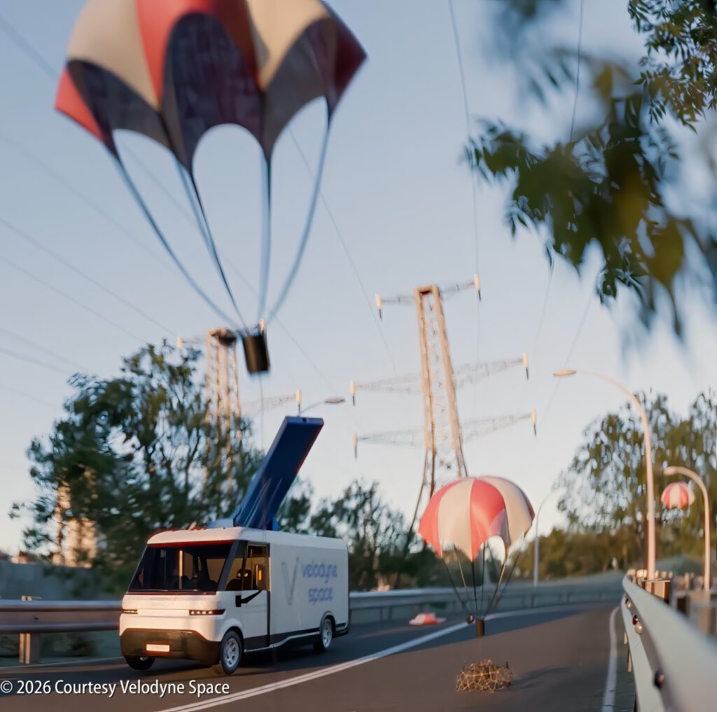A white Velodyne Space van collects objects with parachutes from a road under power lines, during daylight.