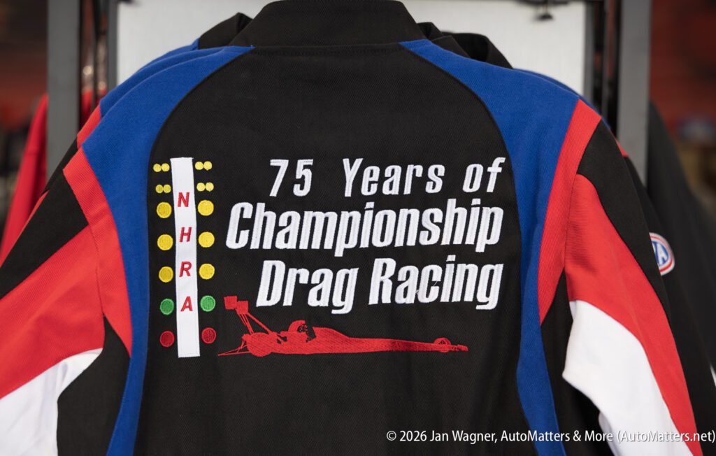 Jacket with "75 Years of Championship Drag Racing" and an NHRA drag racing design on the back, in red, blue, black, and white colors.