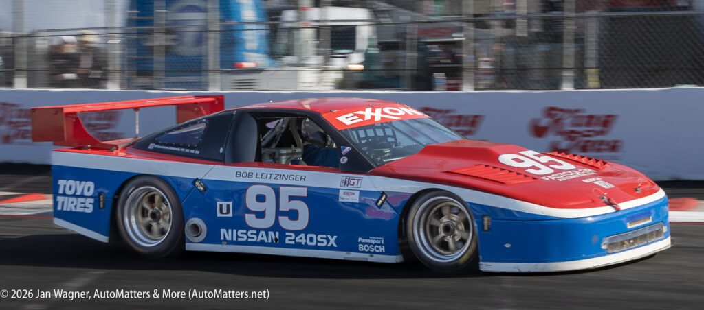 A red, white, and blue Nissan 240SX race car with the number 95 on the track during a race event.