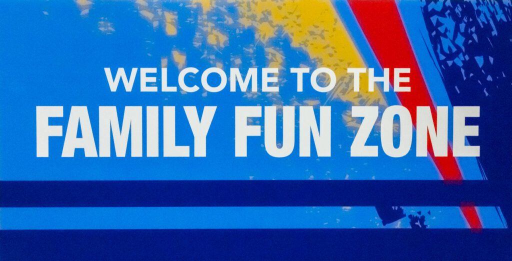 A blue sign with yellow and red accents reads “Welcome to the Family Fun Zone” in bold white letters.