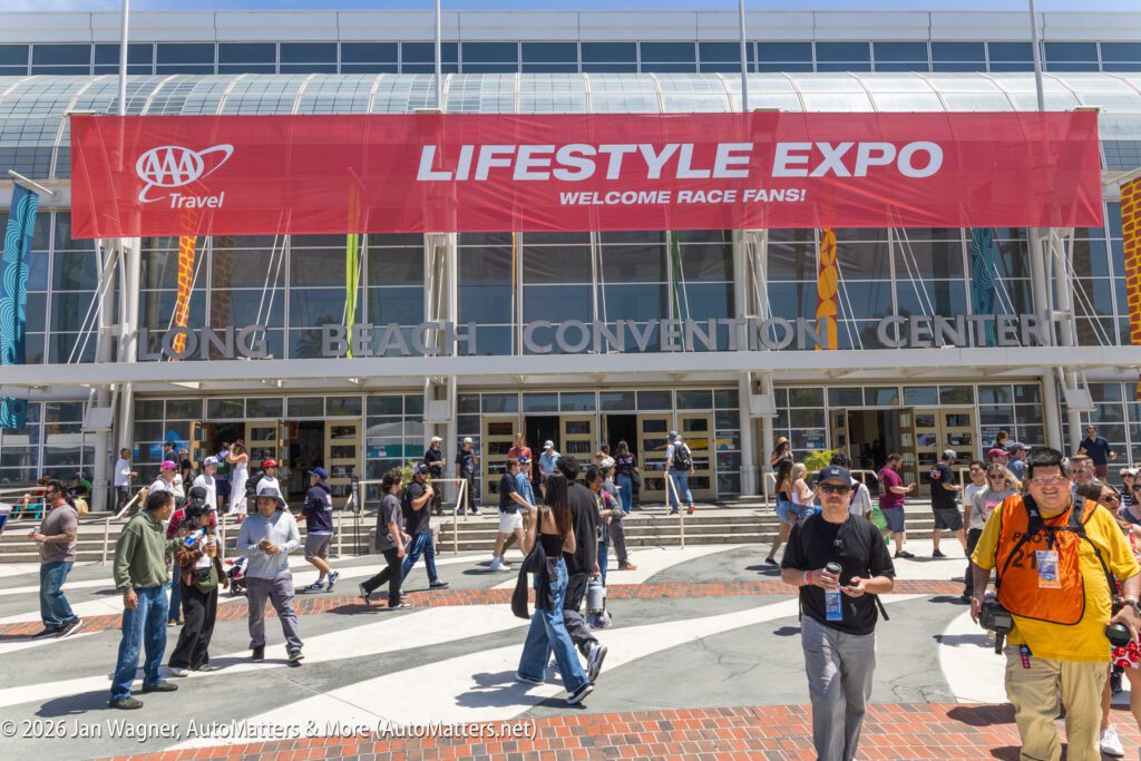 Crowd of people walking outside the Long Beach Convention Center under a large red "Lifestyle Expo" banner that reads "Welcome Race Fans!.