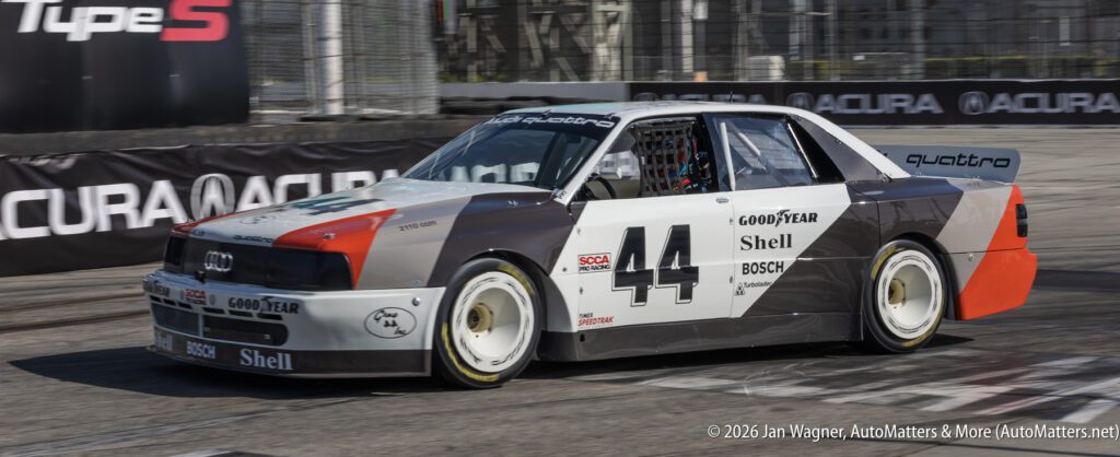 An Audi race car, number 44, with Shell and Goodyear branding, drives on a racetrack during a motorsport event.