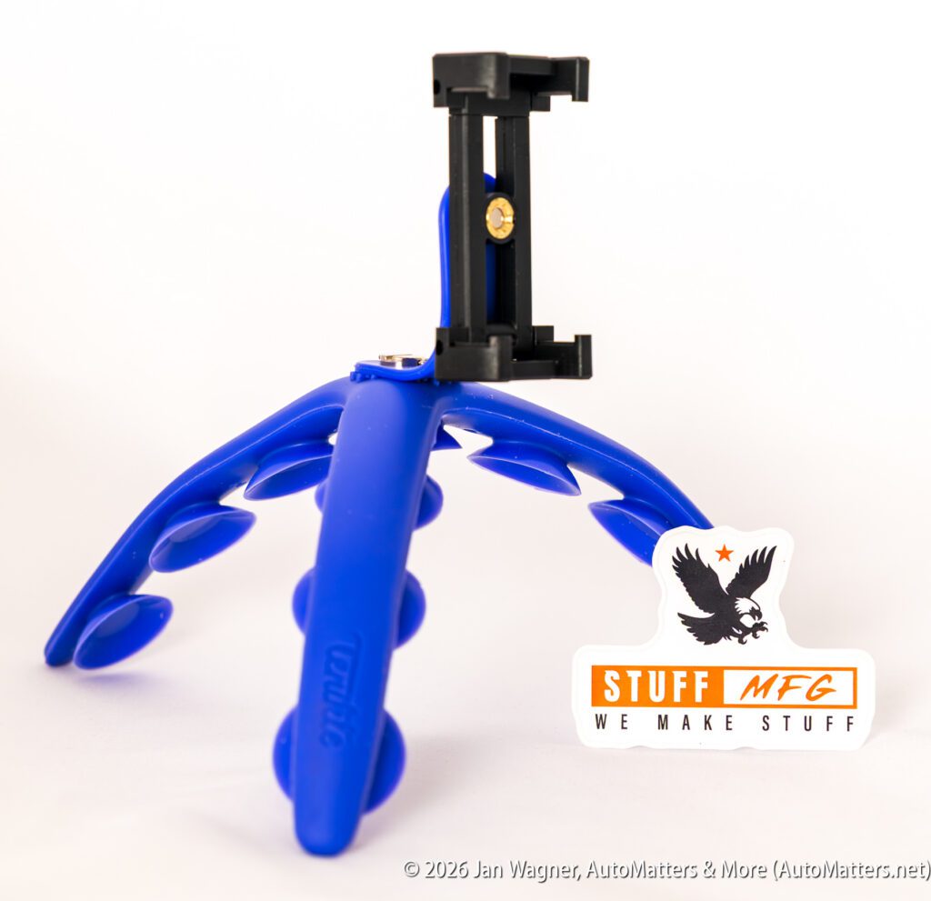 A blue flexible tripod with a phone holder attachment is displayed next to a "STUFF MFG WE MAKE STUFF" sticker on a white background.